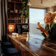 Middle-aged woman enjoys her morning cup of coffee at her kitchen bar, which may contribute to slower aging.