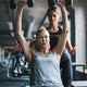 Middle-aged woman lifts weights with a trainer to boost energy.