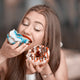 Woman eats two doughnuts illustrating that texture impacts our cravings and how much we eat.
