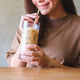 Woman sips iced coffee made with high-protein coffee creamer.