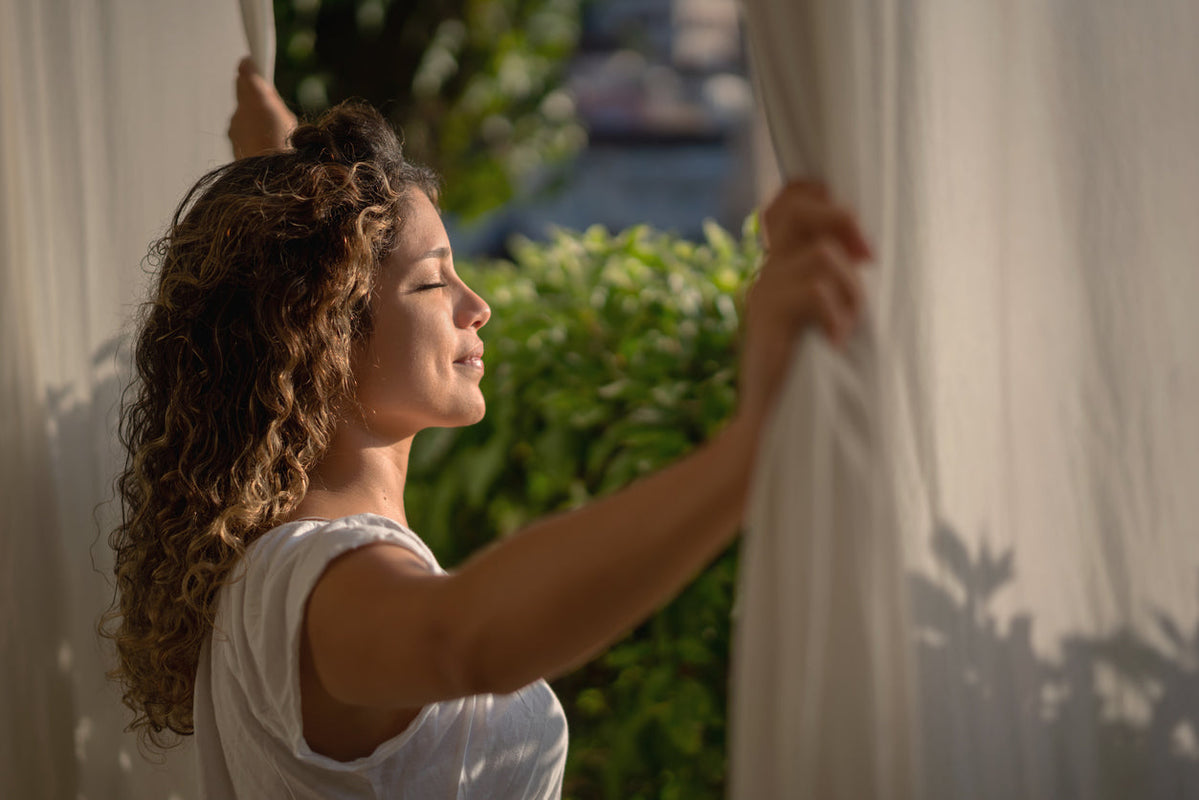Woman wakes up and opens curtains for start her morning routine