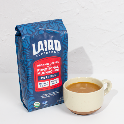 Bag of Laird Superfood organic medium roast whole bean coffee with functional mushrooms next to a cup of coffee.