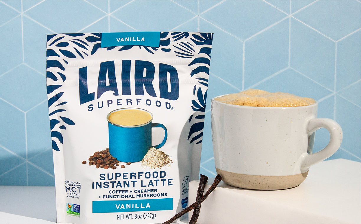 Laird Superfood Vanilla instant latte with a white glass mug filled with latte and vanilla bean next to it.