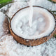 Coconut creamer being poured into a coconut shell, illustrating the rise in popularity of coconut creamer and milk