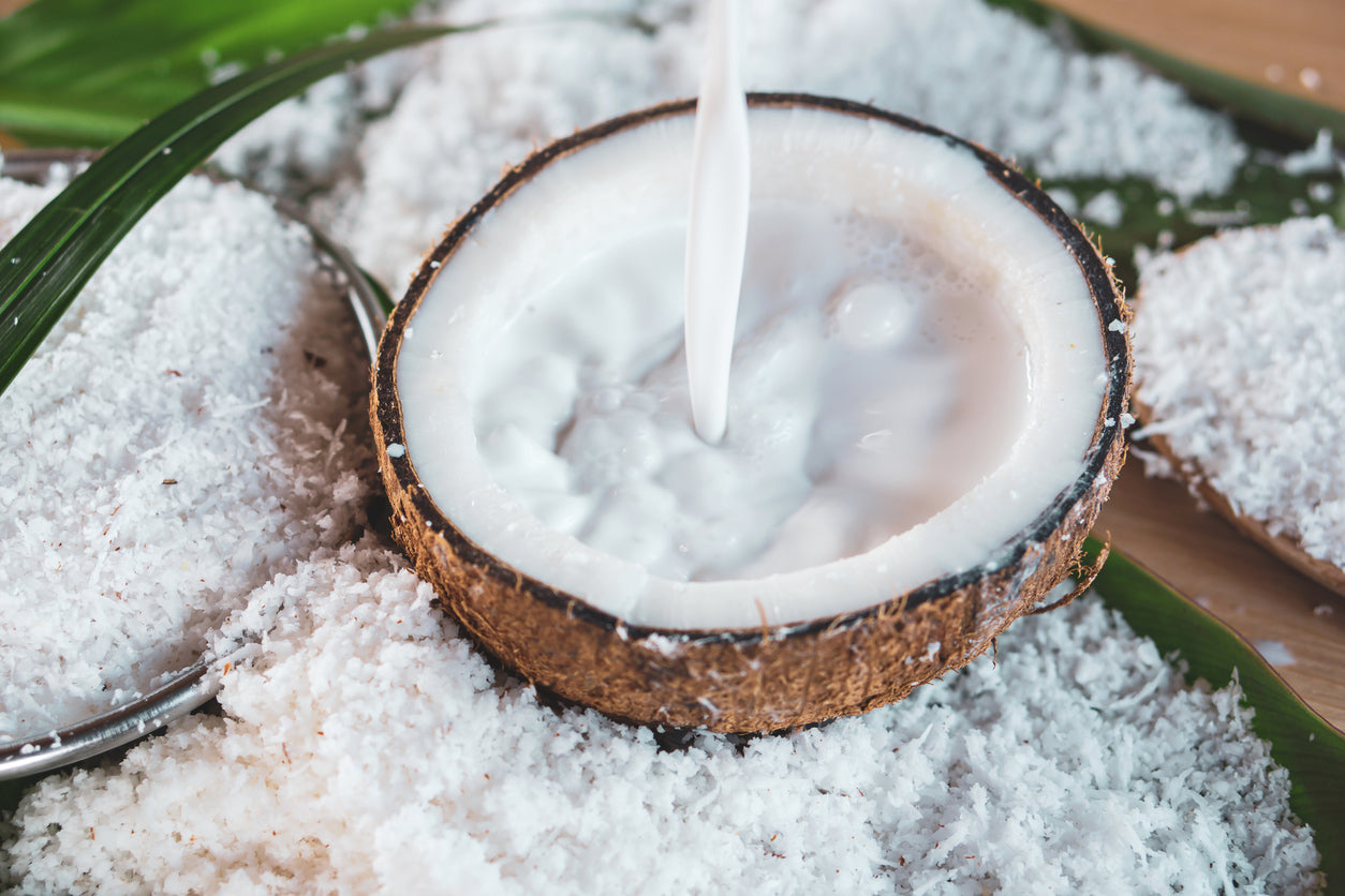 Coconut creamer being poured into a coconut shell, illustrating the rise in popularity of coconut creamer and milk