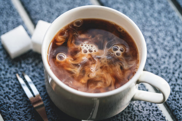Overhead image of a cup of superfood coffee with cream just added.