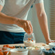 Man adds berries to a yogurt cup,  using various superfoods to make a healthy breakfast.