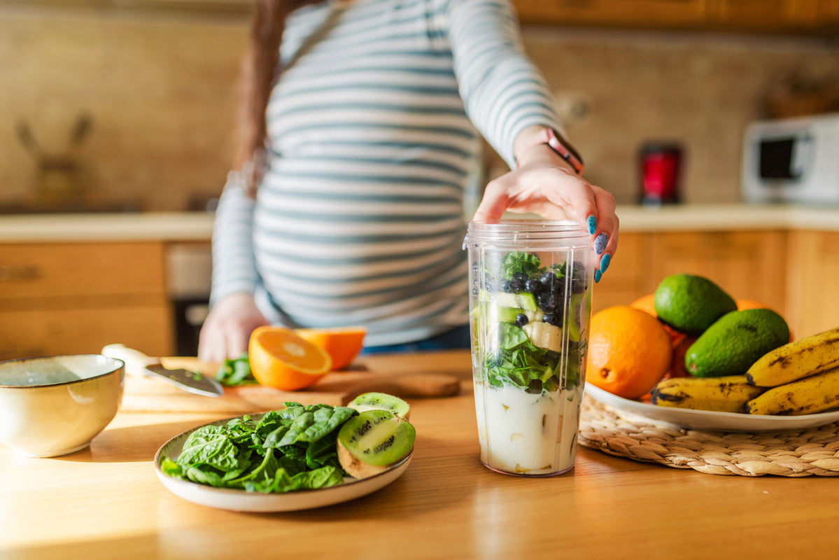 A pregnant mother makes a superfood shake, filled with leafy greens.