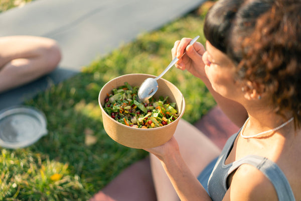 Woman eats a high-fiber salad with ingredients that can combat microplastics. 