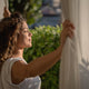 Woman wakes up and opens curtains for start her morning routine
