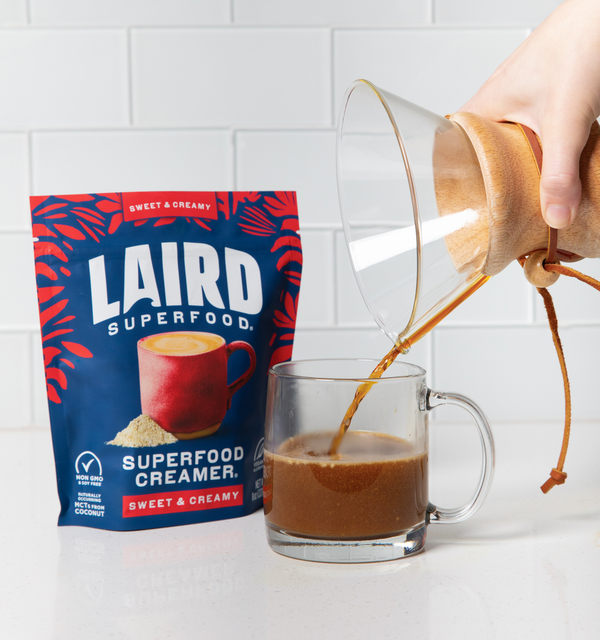 Sweet and Creamy Creamer Bag behind clear coffee mug with coffee being poured into it. 