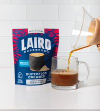 Laird Superfood Sweet & Creamy + Adaptogens Creamer, pouring coffee into a clear mug.