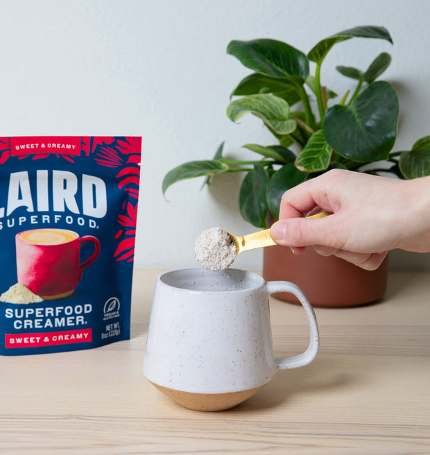 Sweet & Creamy Powder being pored into a mug in front of bag. 