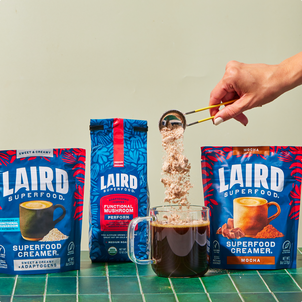 Clear glass mug with Laird Superfood coffee with superfood coffee creamers and the bag of coffee behind it