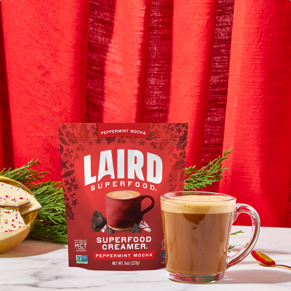 Laird Superfood peppermint mocha creamer package with a cup of coffee and cookies on a red background