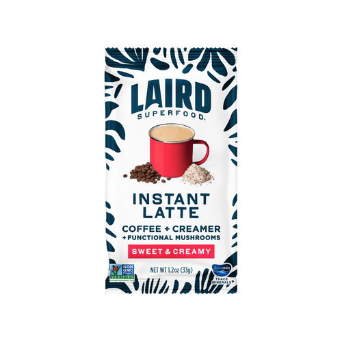 A white Laird Superfood Instant Latte packet with floral graphics and a frothy cup of superfood fueled coffee 